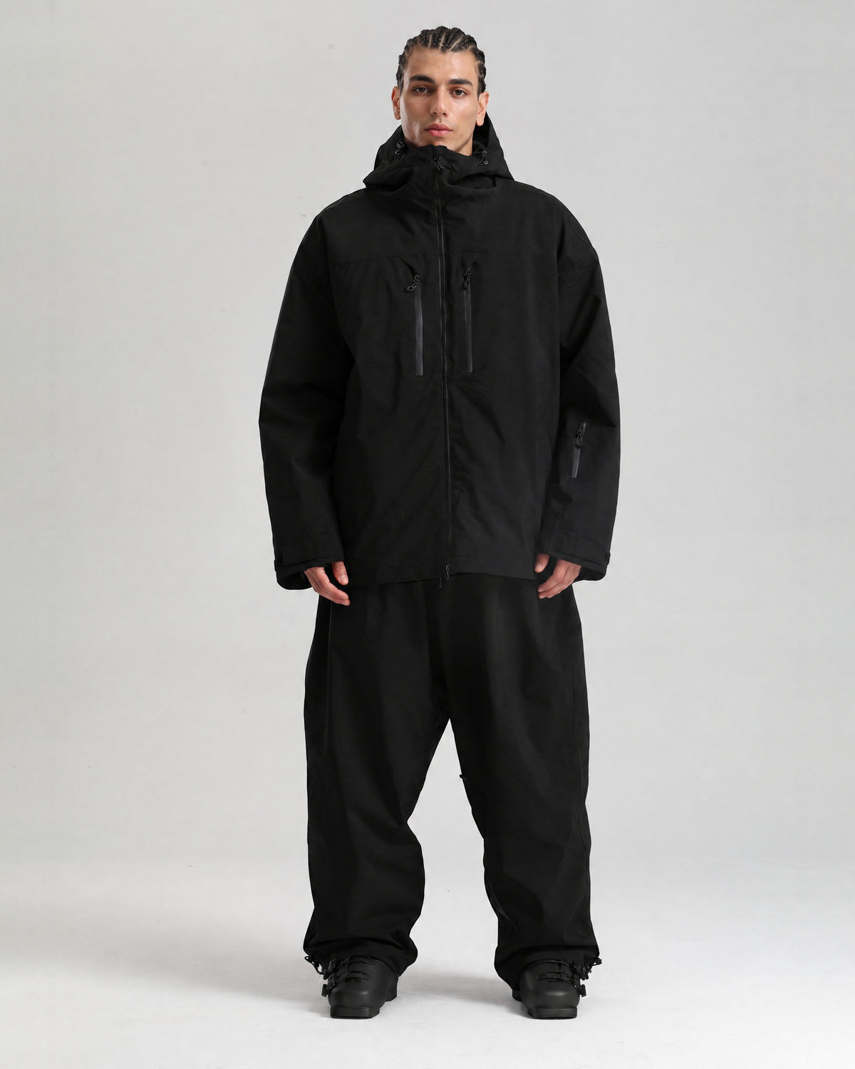 NOJU Core set in black, ski jacket and baggy ski pants, full-length front view with black ski boots