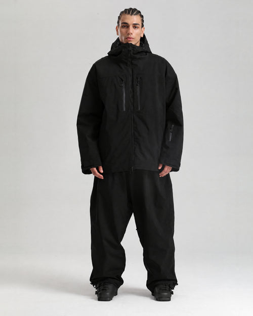 NOJU Core set in black, ski jacket and baggy ski pants, full-length front view with black ski boots