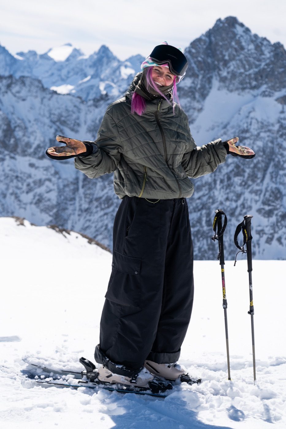 Skier smiling in green jacket and baggy pants