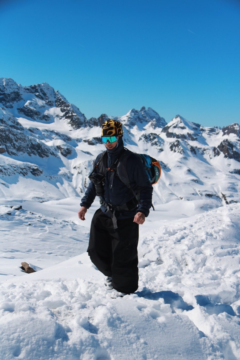 Rider walking snow ridge with backpack